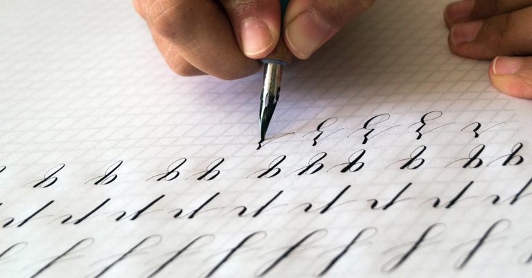 Person practicing calligraphy on a white paper with a pen and ink.