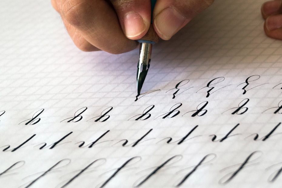 Person practicing calligraphy on a white paper with a pen and ink.